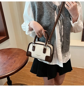 Detail view of a vintage cream and brown bowling bag worn as a crossbody purse