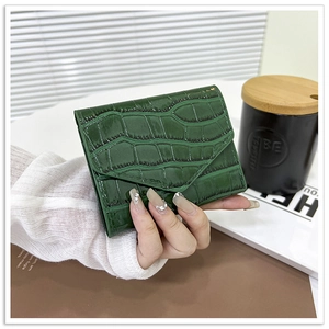 Detalle de textura de cocodrilo verde oscuro en una cartera de tres pliegues