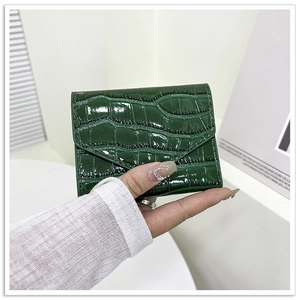 Detalle de mini cartera verde oscuro en cuero brillante con relieve de cocodrilo