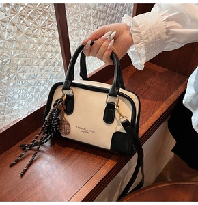 Detail of contrast stitching, leather texture and tennis racket charm on shoulder bag