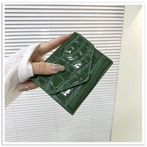 Detalle de cartera de mano verde oscuro con patrón de piedra sobre fondo blanco