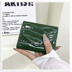 Detalle de cartera verde oscuro con textura de cocodrilo y cierre de solapa triangular
