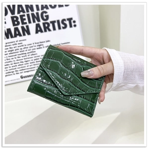 Macro shot of dark green crocodile pattern patent leather envelope wallet held in hand