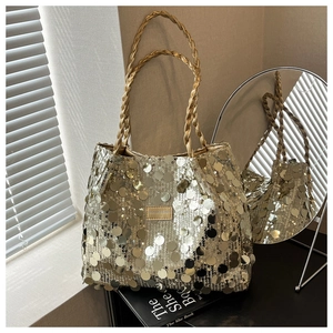 Detail of golden sequin tote bag with woven handles and fashion brand nameplate