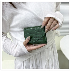 Detail of dark green crocodile embossed leather envelope wallet held in hand