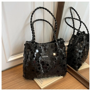 Detail of black sequined tote bag featuring woven leather handles and fashion label