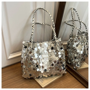 Macro shot of silver sequin tote bag with metallic shine on dark wooden surface