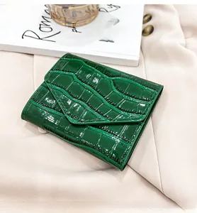 Detalle de la cartera de cuero verde oscuro con patrón de cocodrilo sobre un blazer
