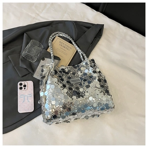 Close-up of silver sequin tote bag with metallic logo plate and braided handle