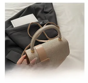 Detail of beige textured handbag with metal woven gloss and round handle on white bedding