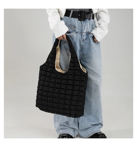 Close-up of black quilted bubble tote bag texture and soft puffed shoulder strap detail
