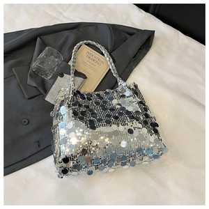 Close-up of silver sequin handbag with woven handles on white textured bedding