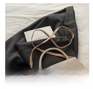 Detail view of khaki woven mini crossbody bag with top handle and shimmering texture
