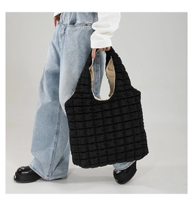 Detail of black quilted tote bag with puffer texture and contrasting beige lining