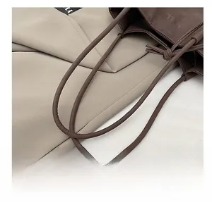 Gros plan sur la poignée en cuir marron du sac cabas avec détail de nœud élégant