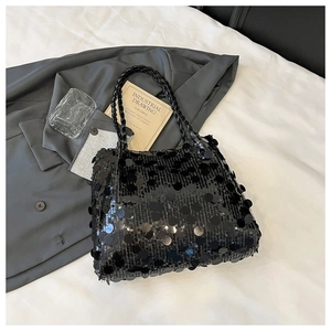 Detailed view of black sequined tote bag with woven handles and glossy light reflections