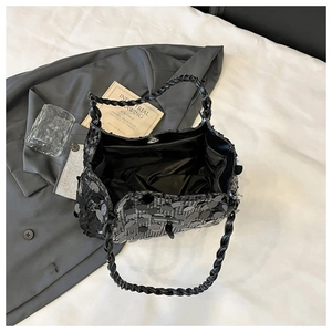 Detail of black sequin tote bag showing silver magnetic closure and woven leather handle