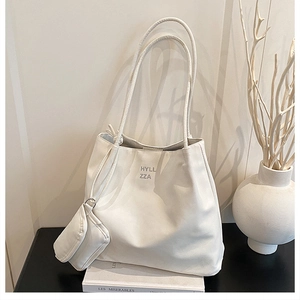 Détail d'un ensemble de cabas blanc cassé avec petite pochette sur livres