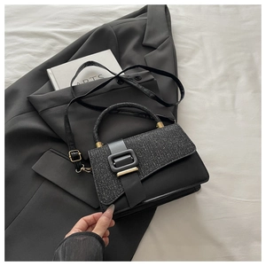 Détail du sac bandoulière vintage noir avec rabat à paillettes et boucle sur un blazer