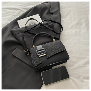 Détail du sac bandoulière noir avec rabat pailleté et boucle dorée mate élégante