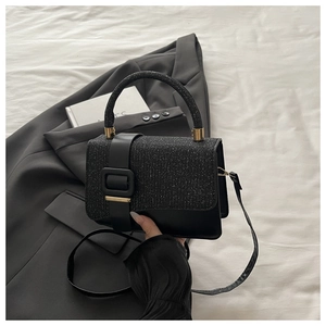 Détail du sac noir avec paillettes argentées sur le rabat et finitions métalliques dorées