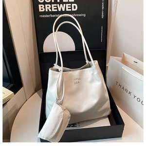 Détail du sac fourre-tout en cuir blanc avec pochette zippée assortie et logo gris imprimé