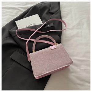 Détail du sac carré rose pailleté sur un blazer sombre montrant texture et ferrures dorées