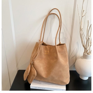 Gros plan d'un sac cabas en daim kaki avec pochette zippée sur un fond minimaliste