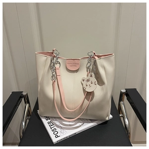 Detail of cream tote bag with pink straps and silver chain handle on a chair
