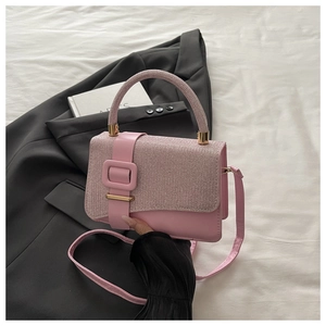Gros plan sur un sac à main rose avec texture pailletée et boucle carrée dorée