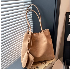 Détail du sac oreiller en tissu Oxford camel et pochette assortie sur un livre
