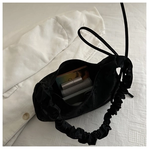 Top view of black satin pleated handbag showing interior storage for daily essentials