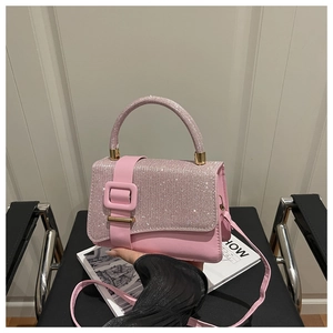 Détail d'un sac à main rose pailleté avec une grande boucle carrée et fine bandoulière