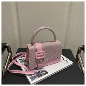 Gros plan du sac carré rose en strass avec boucle dorée sur une chaise noire