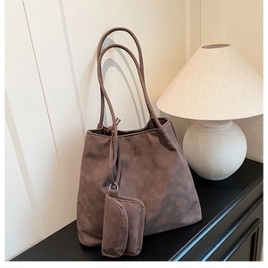Détail d'un sac cabas en daim marron avec petite pochette assortie et logo embossé