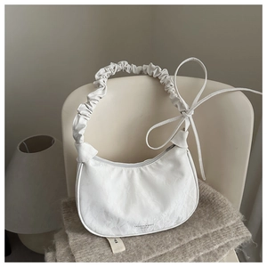Detail of white crescent bag with wrinkled texture and decorative side ribbons