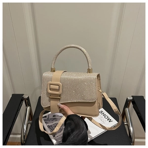 Détail du sac carré strassé couleur champagne sur un magazine au décor élégant