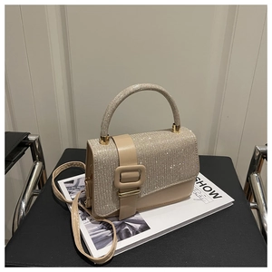 Gros plan sur un sac à main beige carré à paillettes avec une grande boucle décorative