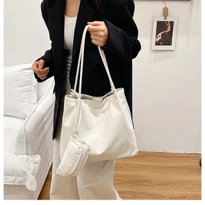 Gros plan d'un ensemble de sac fourre-tout crème avec petite pochette et texture cuir souple