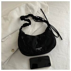Detail of black marble textured shoulder bag with pleated strap and brand logo