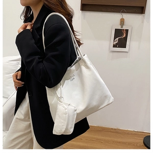 Détail d'un grand sac fourre-tout blanc en similicuir avec fines anses et mini pochette