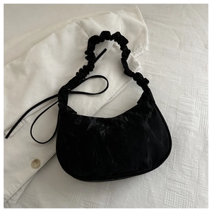 Detailed close-up of a black cloud-textured crescent bag with a pleated shoulder strap