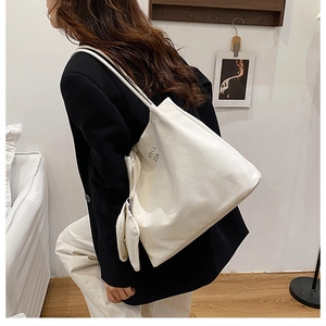 Détail du grand sac cabas blanc avec logo noir et mini pochette suspendue assortie