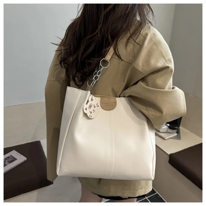 Close-up of off-white tote bag with brown leather label and cute cat charm decoration