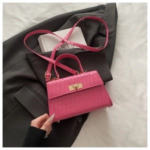 Détail du sac à bandoulière rose motif crocodile avec fermoir rotatif doré sur veste