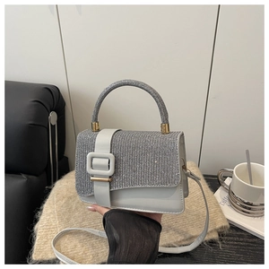 Détail d'un sac bandoulière gris clair orné de strass argentés et de finitions dorées