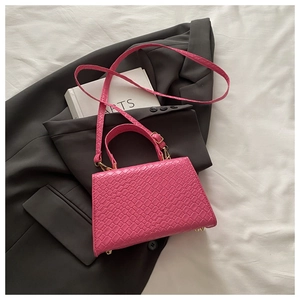 Détail du sac à main rose vif texture crocodile avec ferrures dorées et poignée de toit