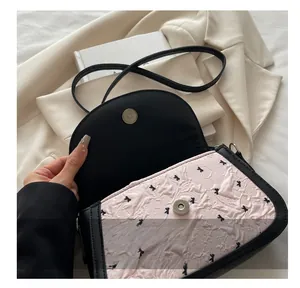 Détail du fermoir magnétique en métal sur le sac à bandoulière rose texturé à nœud