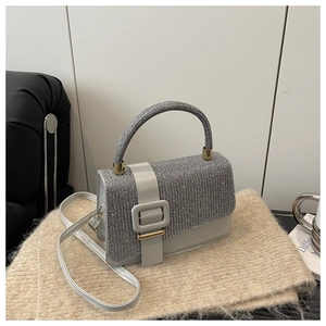 Gros plan d'un sac carré argenté avec texture scintillante et grande boucle dorée