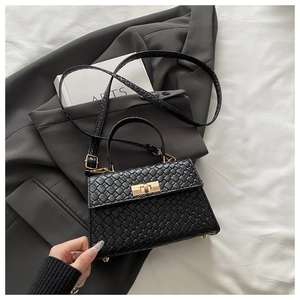 Détail du mini sac tressé noir avec fermoir rotatif et finitions en métal doré